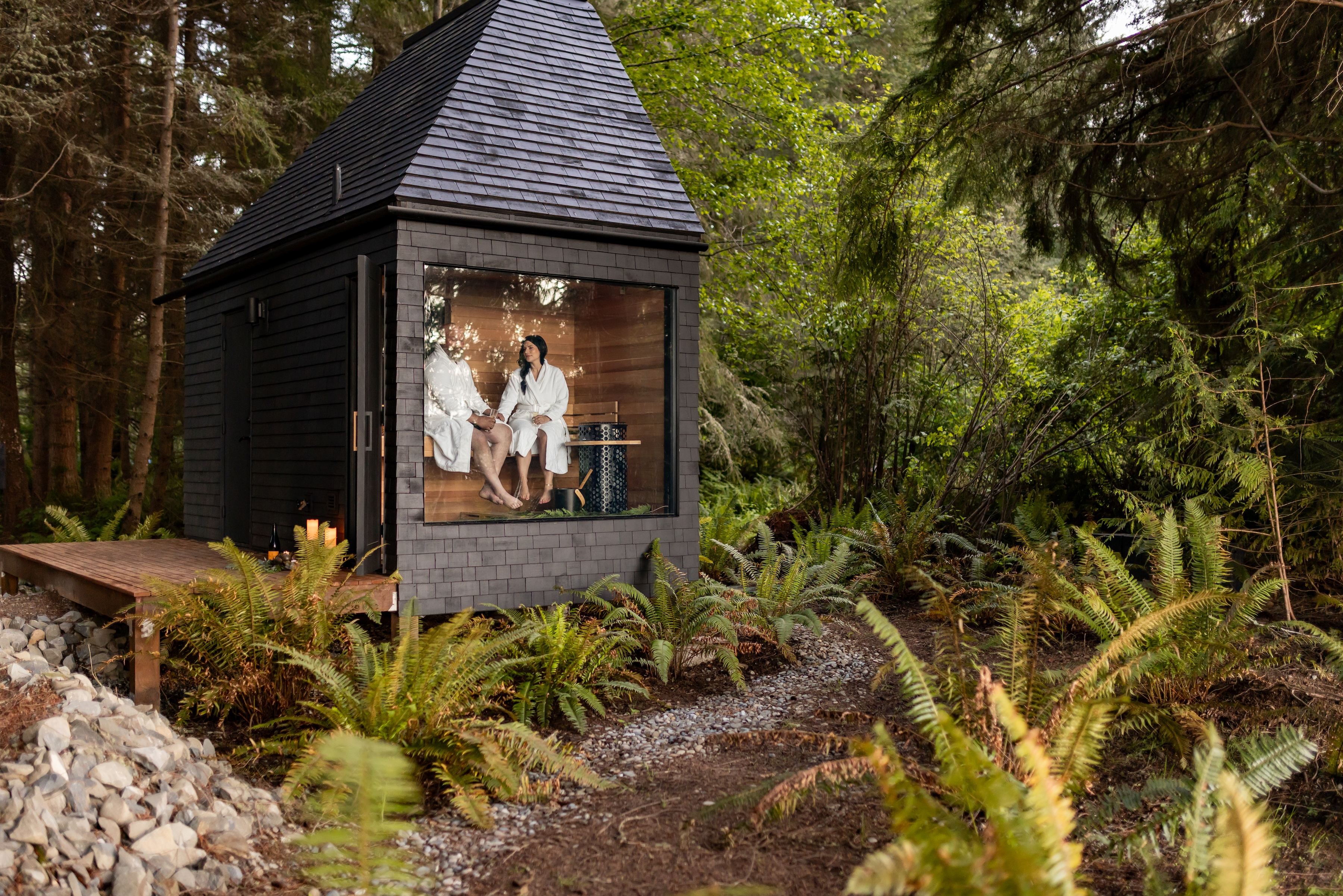 A couple seated together in a private cedar sauna at Menizei on the Olympic Peninsula, experiencing The Distillery ritual surrounded by forest.