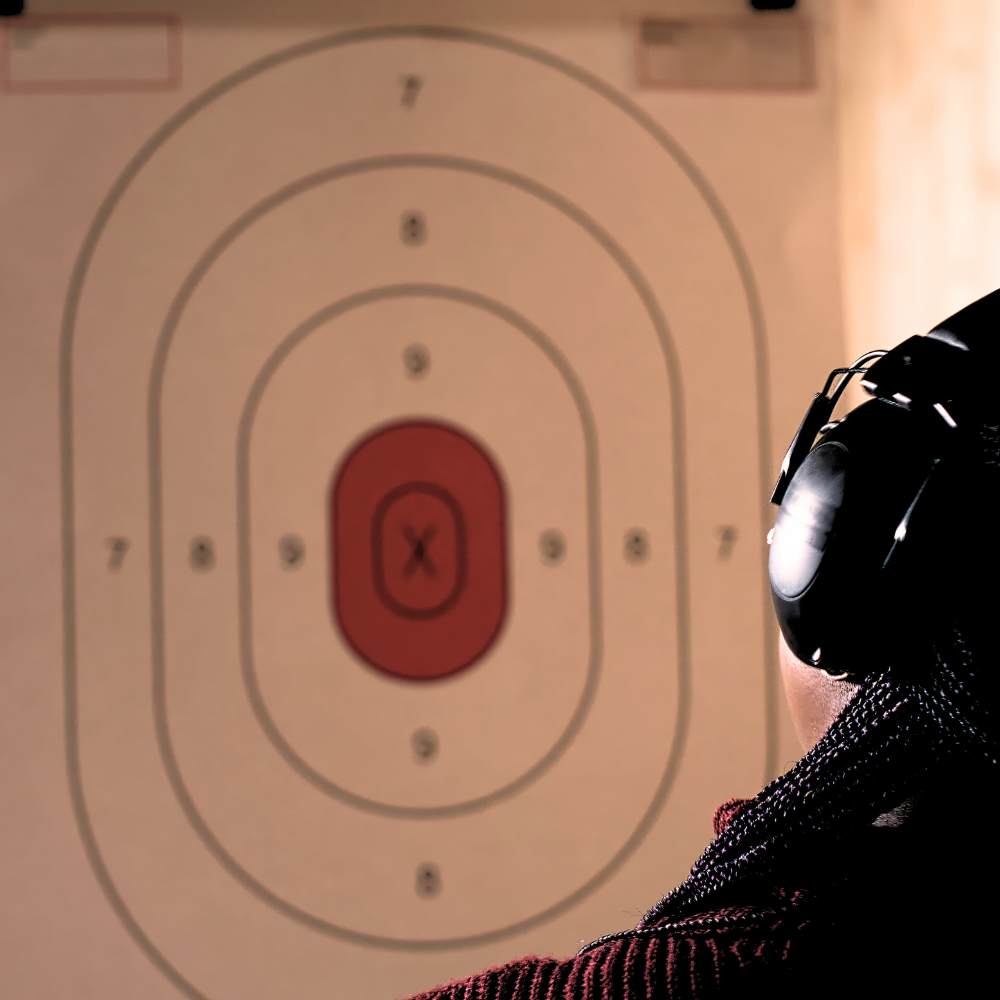 A person wearing headphones focuses intently on a target in front of them.