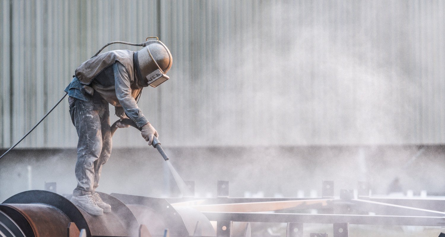 Industrial abrasive blasting worker cleaning commercial surface