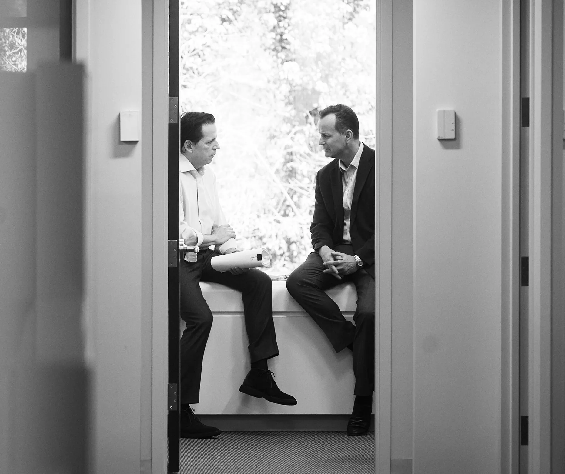 Charles Harper and Igor Acosta having a discussion next to a window