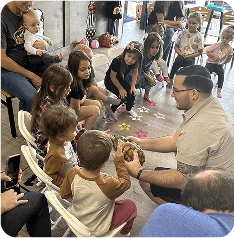 An image of  Children seated in a circle with an instructor during a group activity.