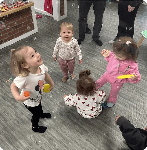 An image of toddlers playing with bubbles and toys at an indoor play center.