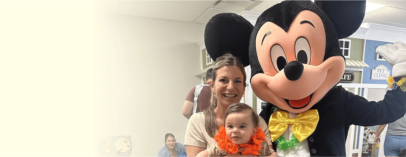 An image of  a mother and child posing with Mickey Mouse character at Little Laughs Playtime