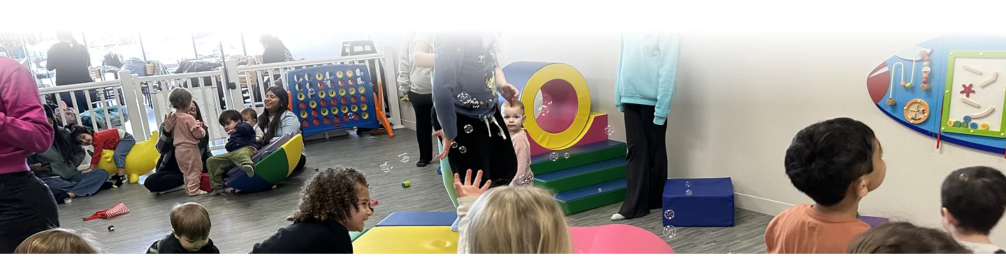 An image of Children enjoying play activities in an indoor soft play area while adults supervise