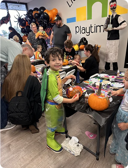 An image of parents and kids gathered around a snack and craft table during a party.
