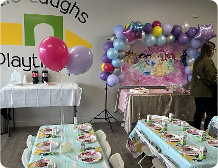 An image of a pastel-themed birthday table with balloons, snacks, and decorations.