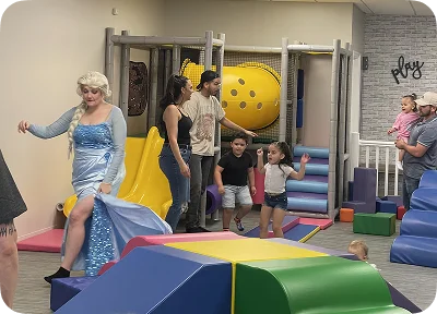 An image of kids playing on soft play equipment with slides and foam blocks.
