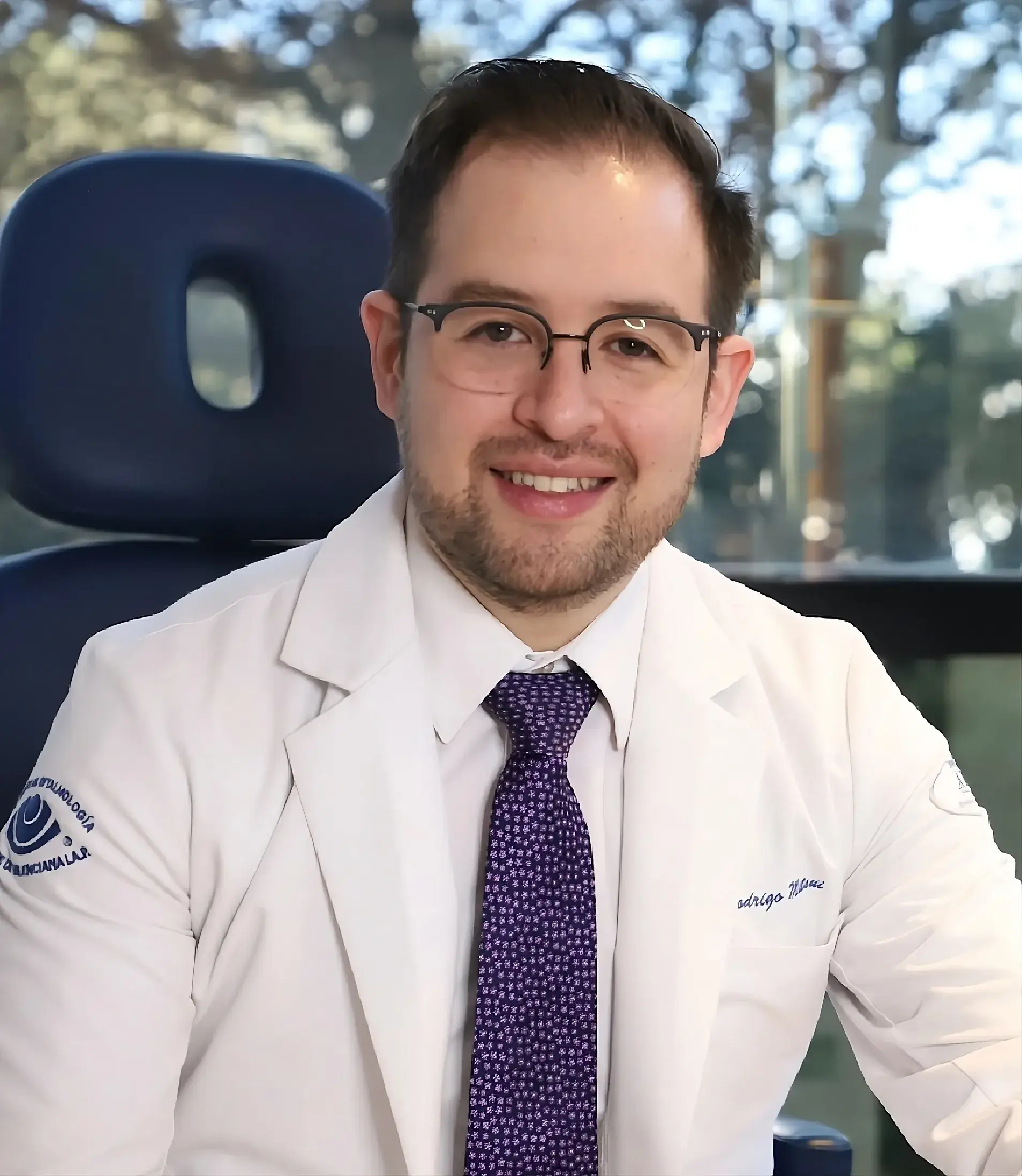 Fotografía profesional del Dr. Rodrigo Matsui sonriendo en uniforme médico, especialista en retina y cirugía oftalmológica en CDMX.