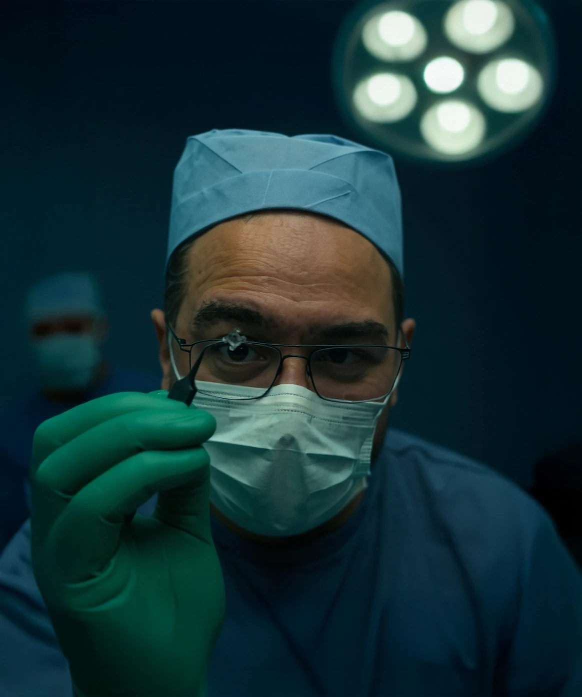 Dr. Jesús Arrieta en quirófano sosteniendo un lente intraocular para cirugía de catarata