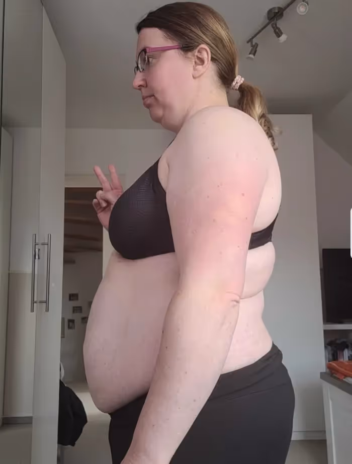 Eine Frau in Sport-BH und Hose zeigt das Friedenszeichen.