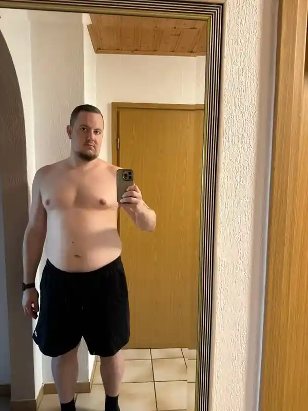 Ein Mann ohne Hemd macht ein Selfie im Spiegel.
