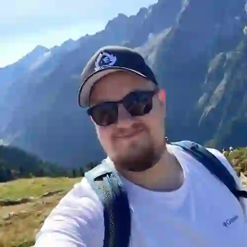 WPF Community - Ein lächelnder Mann mit Sonnenbrille und Baseballkappe vor einer Berglandschaft.