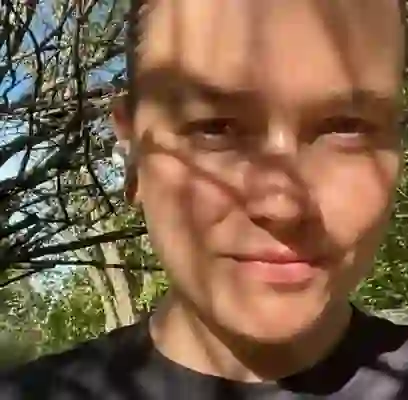 WPF Community - Eine Frau mit zurückgebundenen Haaren und Ohrhörern lächelt in der Sonne.
