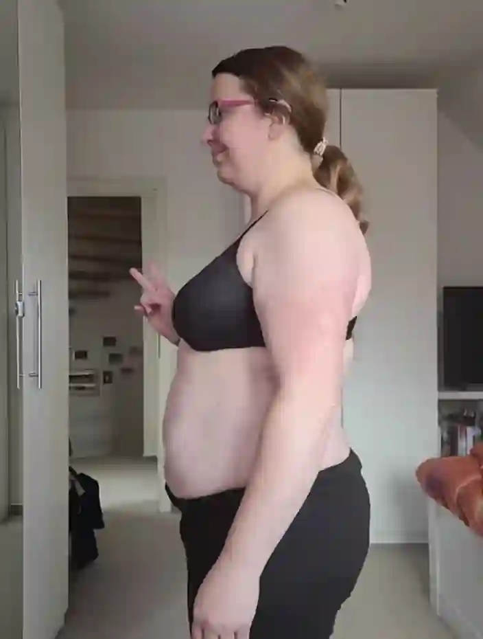 Eine lächelnde Frau in Sport-BH und Hose zeigt das Friedenszeichen.