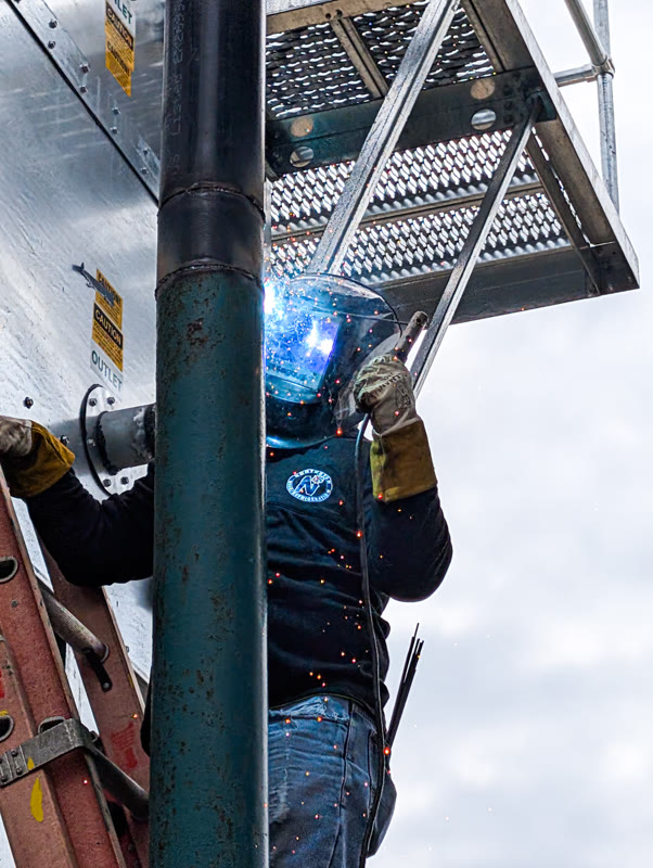 Northstar Refrigeration technician welding industrial refrigeration piping on an elevated platform