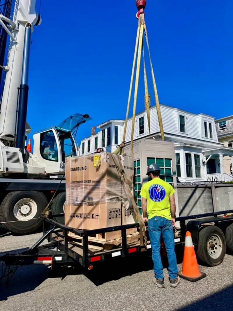 Northstar Refrigeration crew guiding a crane lift of commercial HVAC equipment during a job site delivery