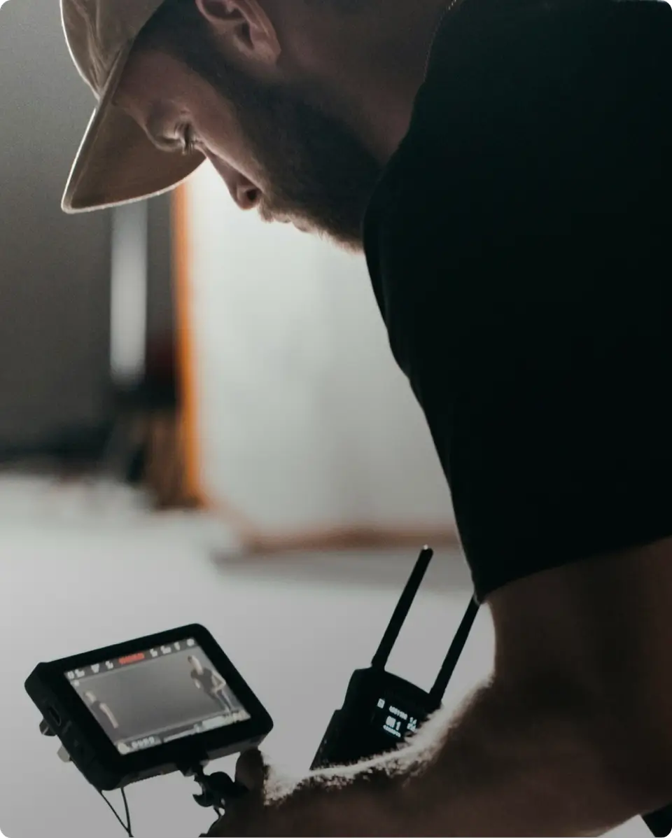A man in a hat looking at something on a tablet.