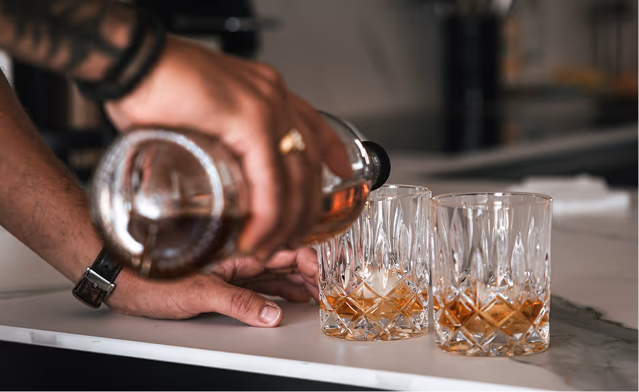 Homme versants du whisky dans un verre