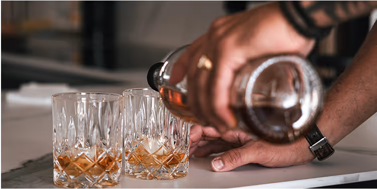 Homme versants du whisky dans un verre