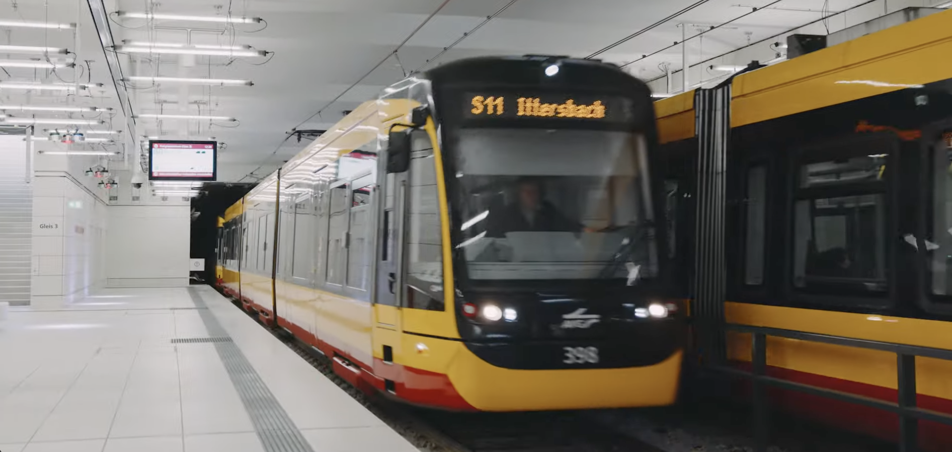 Moderne gelb-schwarze Karlsruher Stadtbahn in einer hellen, unterirdischen Haltestelle, die zukunftsweisende Stadtentwicklung und Infrastruktur visualisiert.