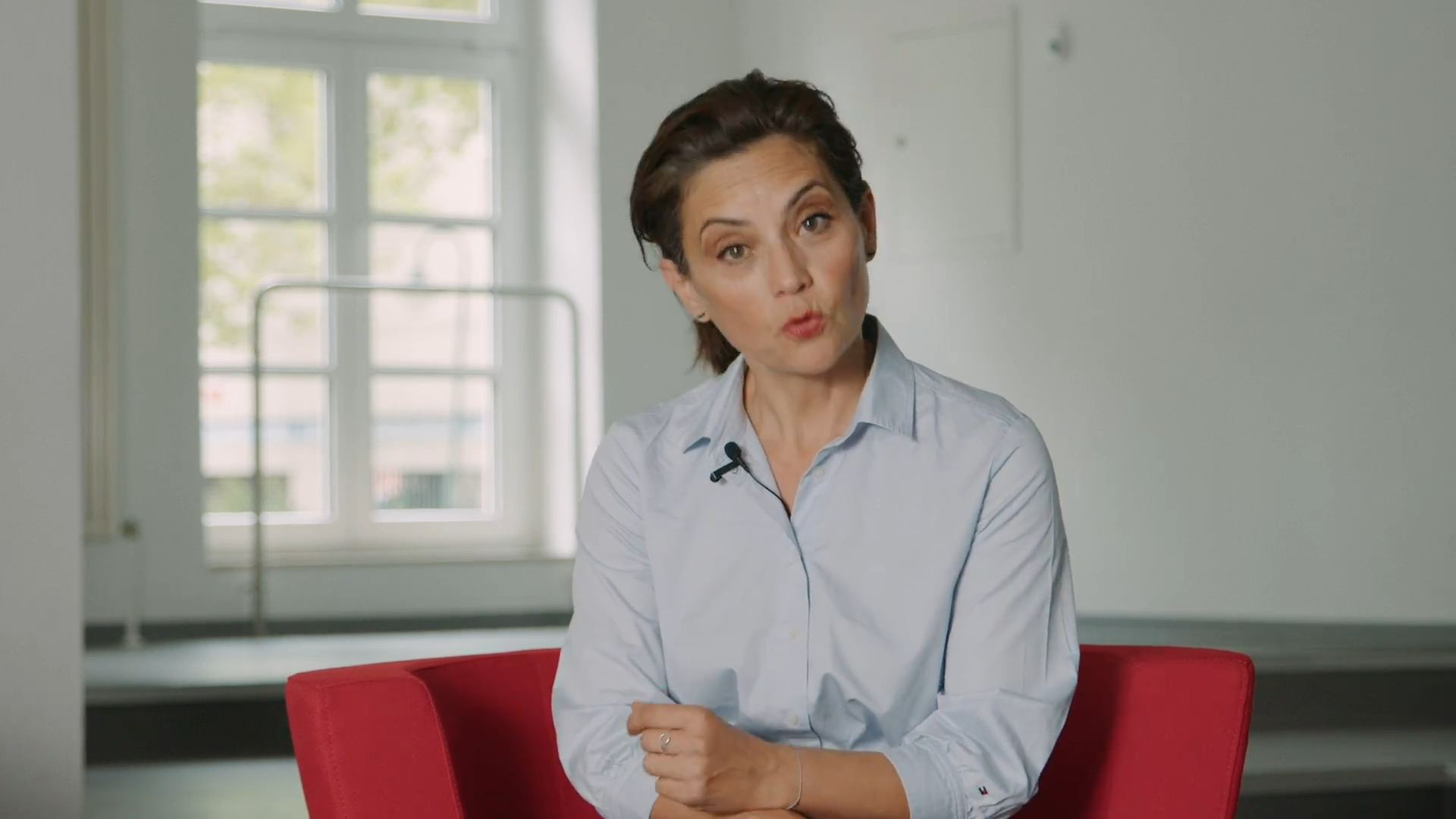 Frau mit Mikrofon in hellem Studio, spricht über soziale Projekte Karlsruhes (Imagefilm).