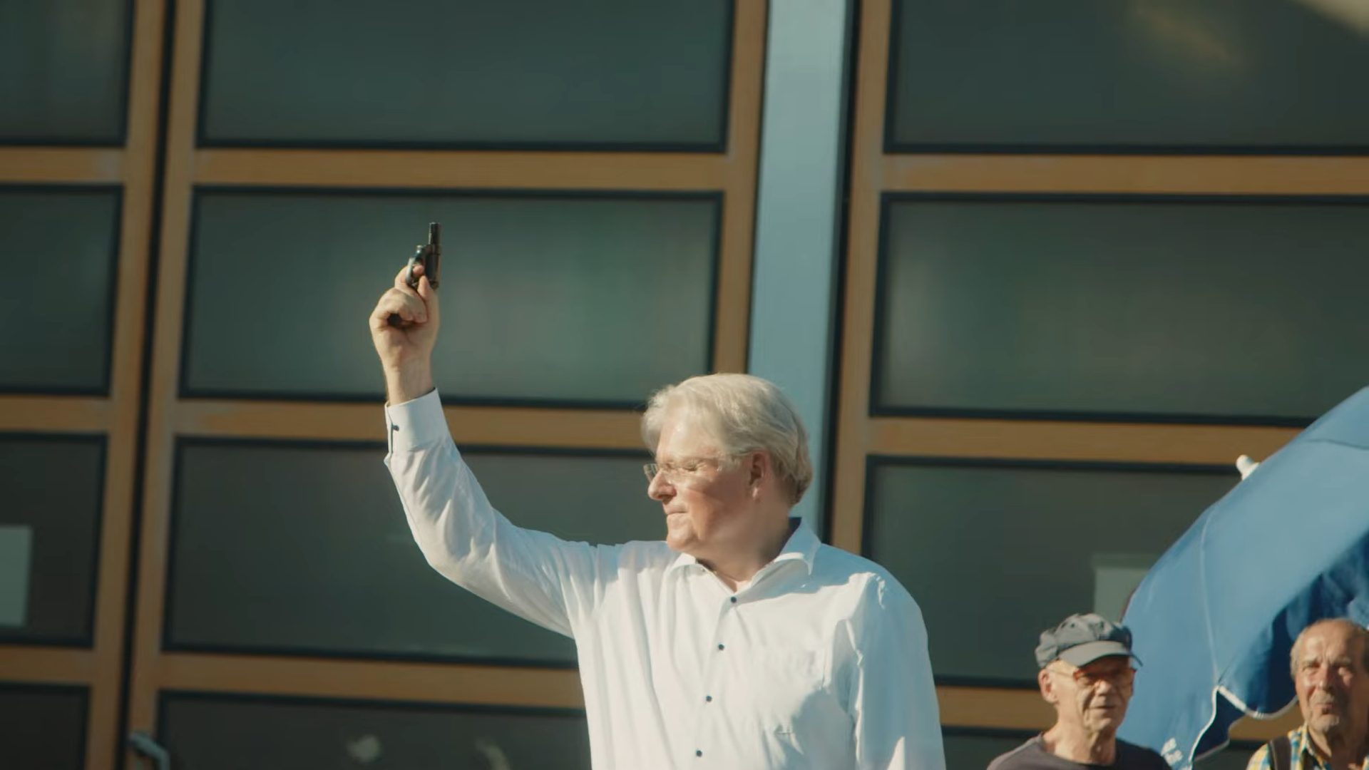 Offizieller gibt Startschuss für den Volkslauf mit Startpistole. Helle, dynamische Szene des Eventfilms.