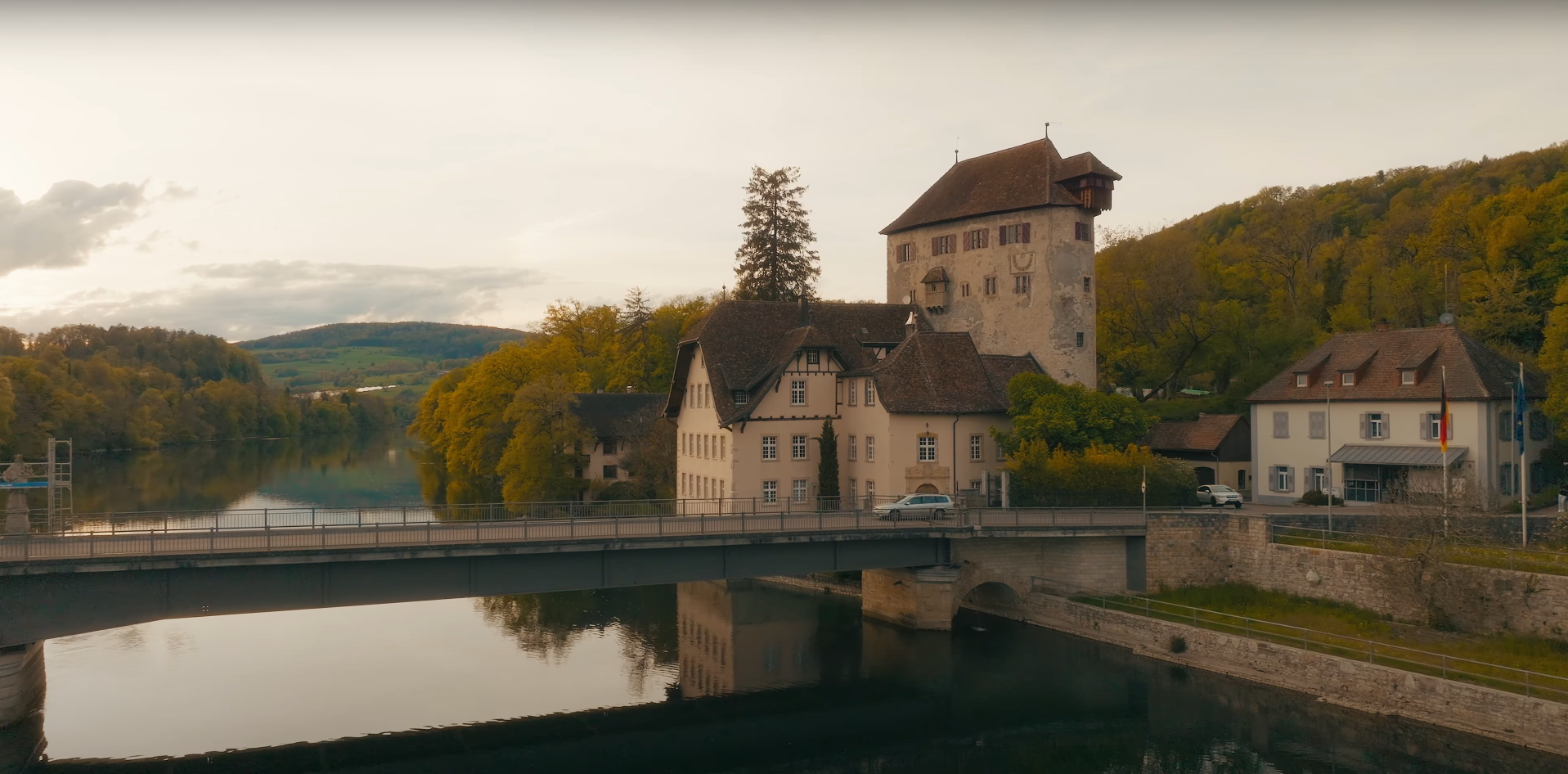 Luftaufnahme von Hohentengen: Historisches Schloss, Brücke und Rathaus an einem Flussufer, umgeben von grünen Wäldern.