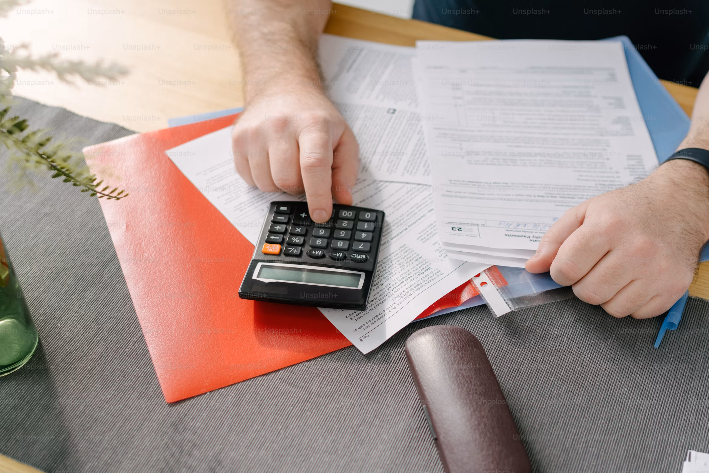 Main d’une personne utilisant une calculatrice sur des documents administratifs pour estimer les économies d’énergie réalisées grâce aux panneaux solaires Sunlib.