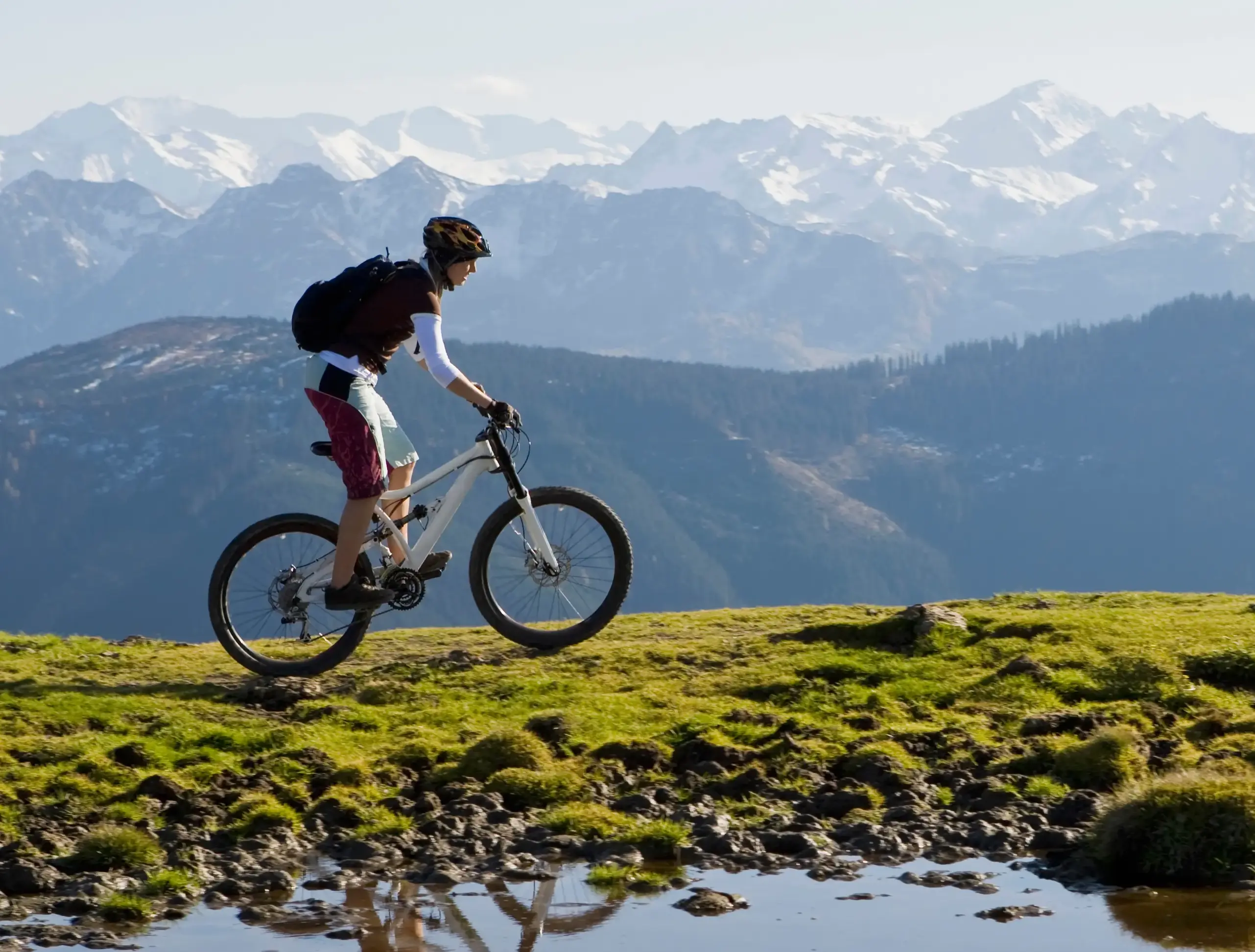 Fahrende Mountainbikerin in den Bergen auf einer Anhöhe mit weiter Aussicht
