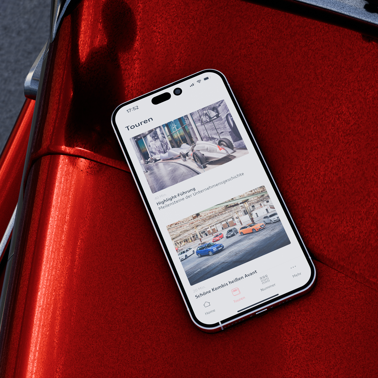 Ein iPhone Mockup auf einer roten Motorhaube worin die Audi Tradition App, auf der verschiedene Touren ausgewählt werden können, zu sehen ist