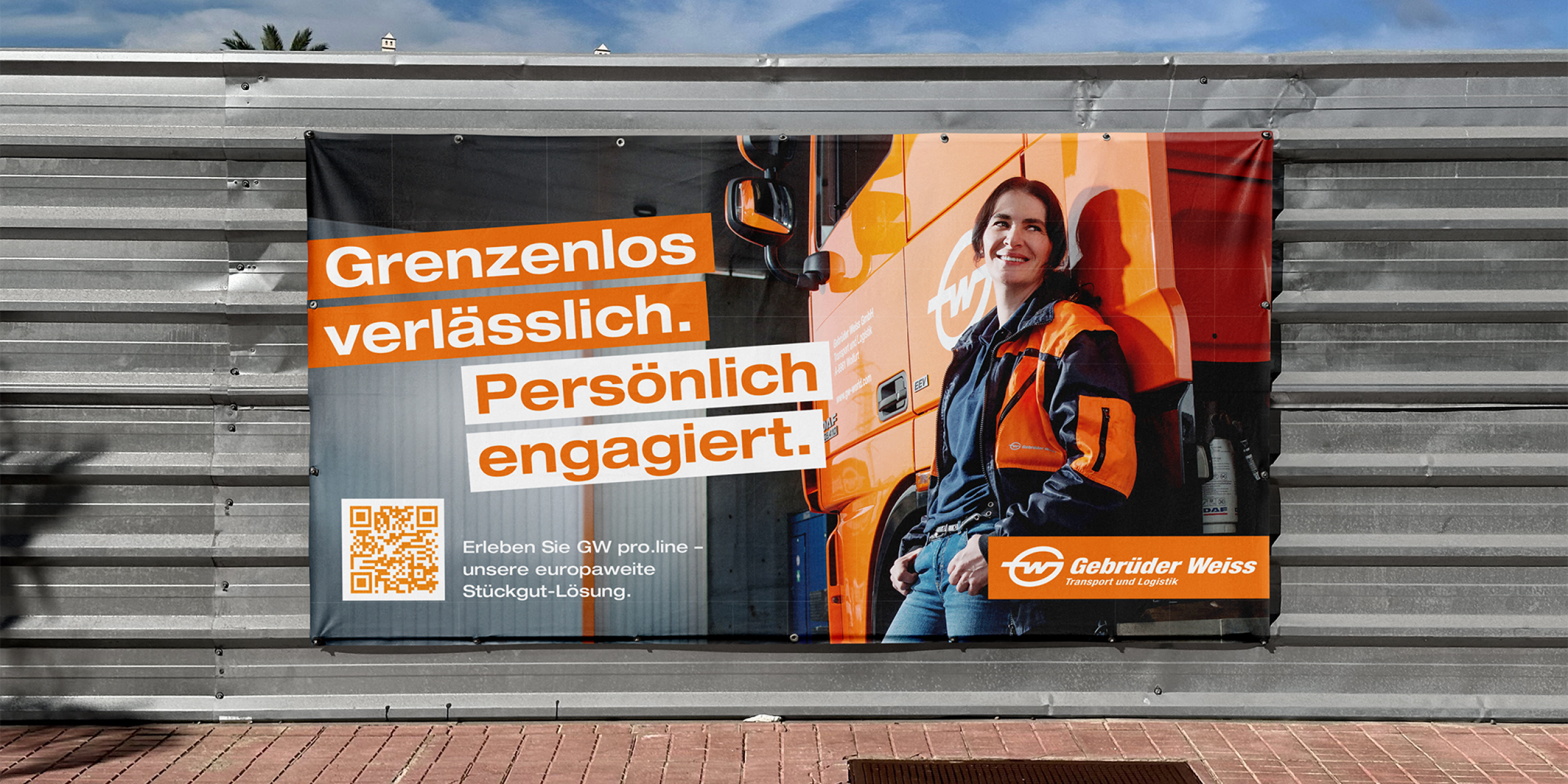 Eine große Bauzaunplane der Gebrüder Weiss mit dem Schriftzug "Grenzenlos verlässlich. Persönlich engagiert."