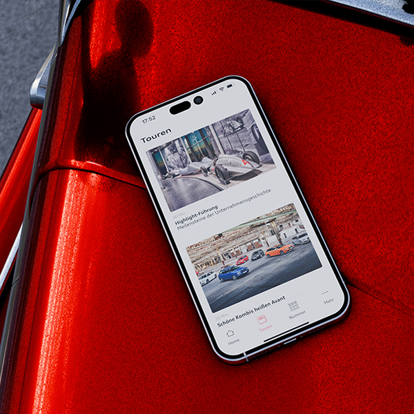 Ein iPhone Mockup auf einer roten Motorhaube worin die Audi Tradition App, auf der verschiedene Touren ausgewählt werden können, zu sehen ist