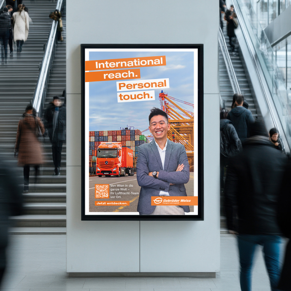 Ein Plakat mit dem Schriftzug "International reach. Personal touch." der Gebrüder Weiss hängt im urbanen Raum.