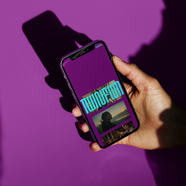 Eine Hand hält ein Smartphone auf dem die lila TwinFilm Website zu sehen ist