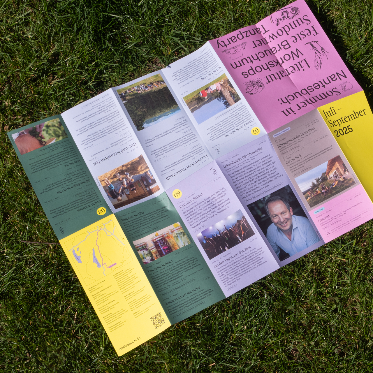 Ein farbenfroher, knalliger Faltflyer mit dem Programm der "Stiftung Kunst und Natur" liegt im Gras