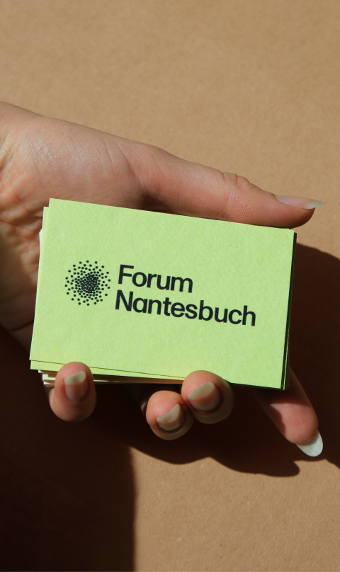 Hand hält eine grüne Visitenkarte des Forum Nantesbuch