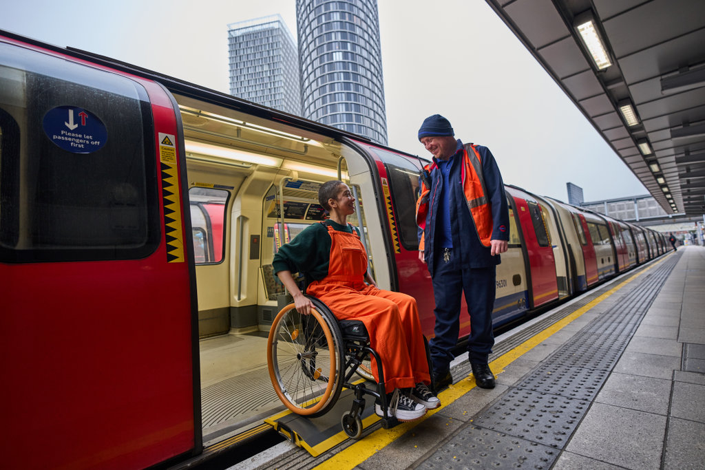 A TfL employee helping a wheelchair user off of the train.