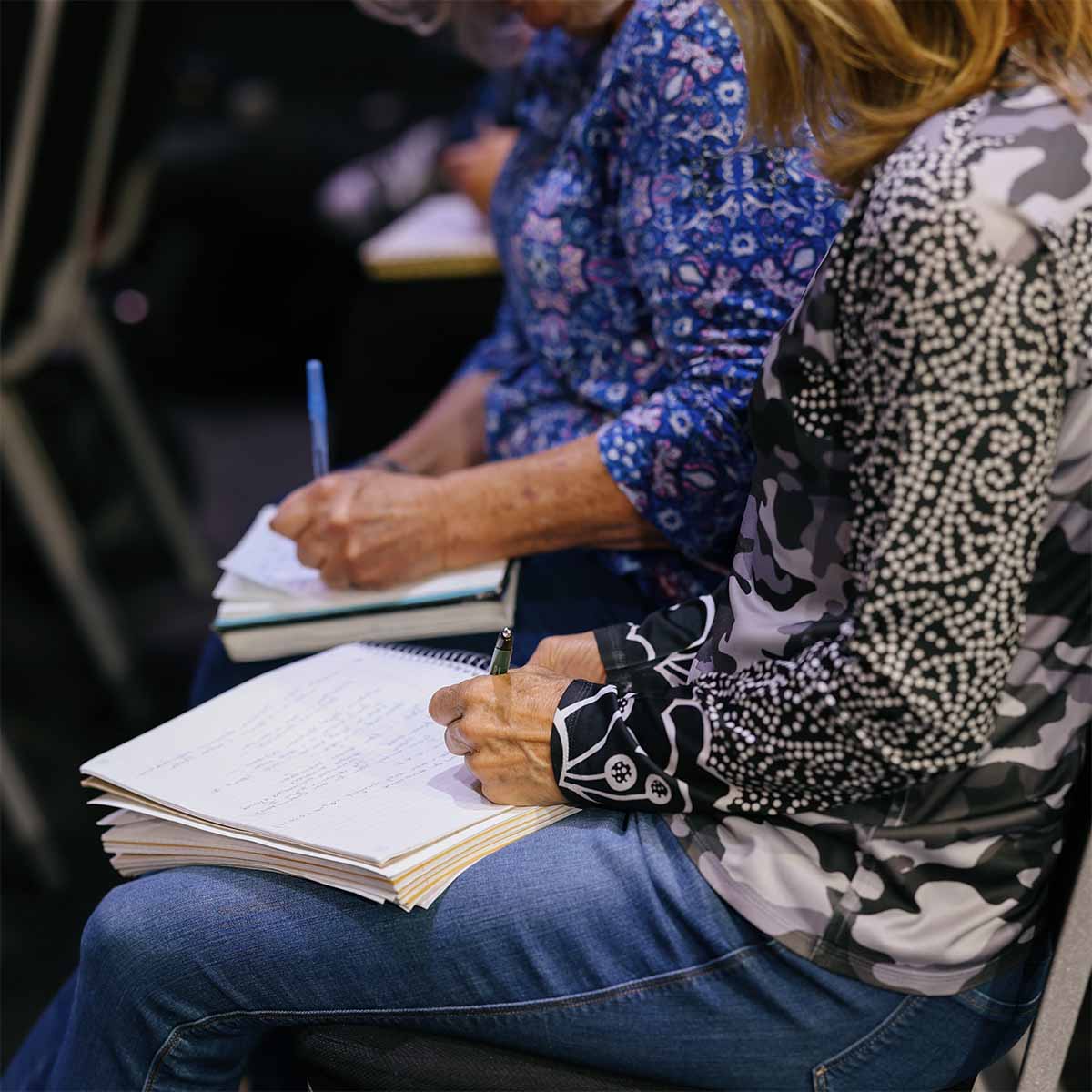 Two women taking notes during class