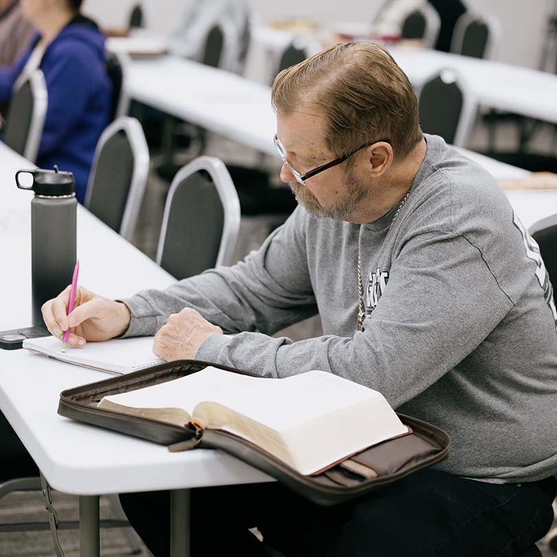 Student studying Bible during class at KINEO