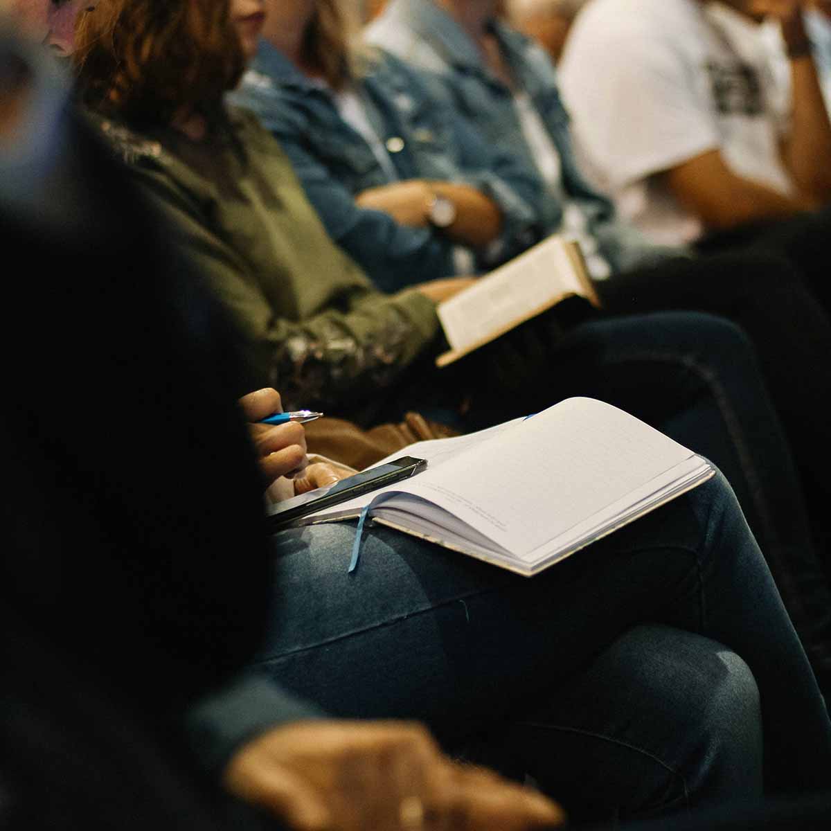 Woman sitting in Sunday morning church service, taking notes.