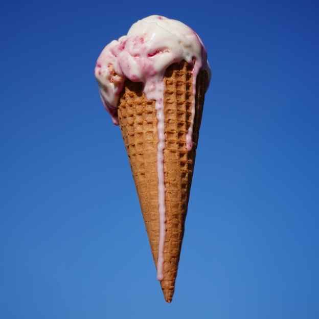 Pink ice cream cone with wafer cone against bright blue background