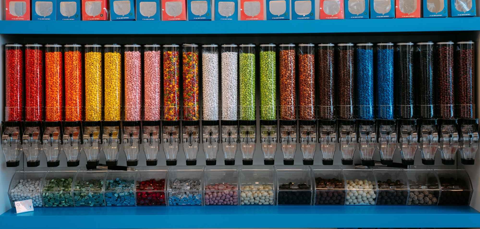 Candy vending machine display with colorful dispensers filled with various colored candies and beads