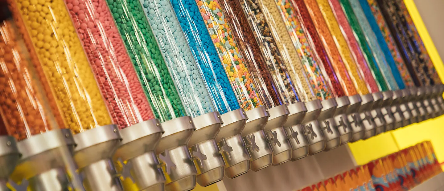Row of colorful paint cans with metal bands arranged in a spectrum of bright hues.