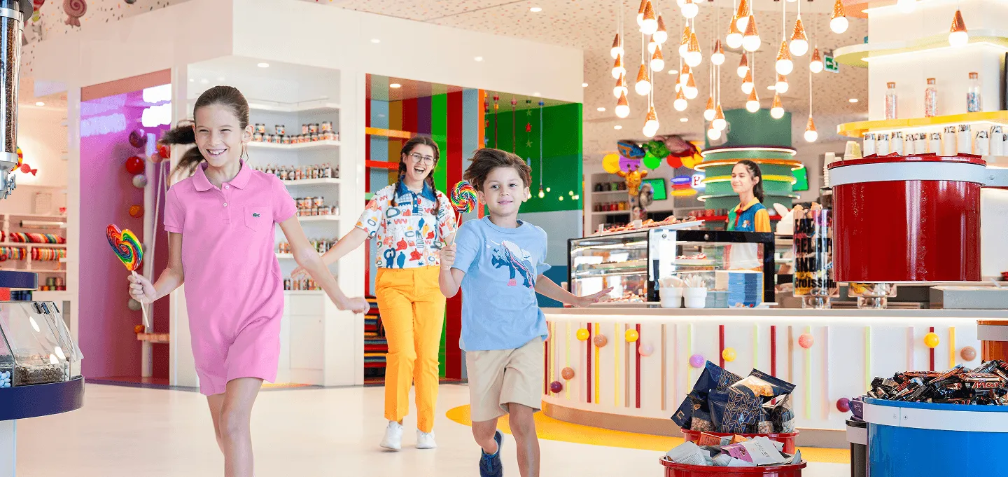 Adult and children enjoying colorful candy store with hanging decorations and merchandise
