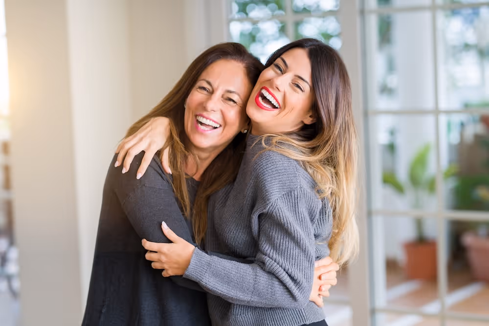 Two women hugging each other in a room.