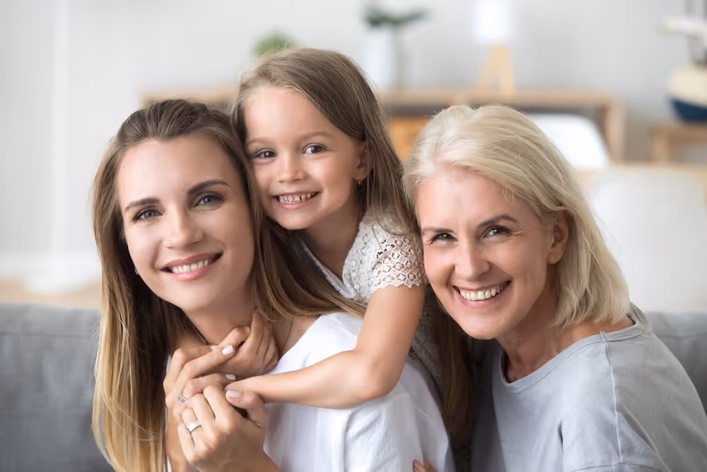A two woman and and a girl are smiling for the camera.