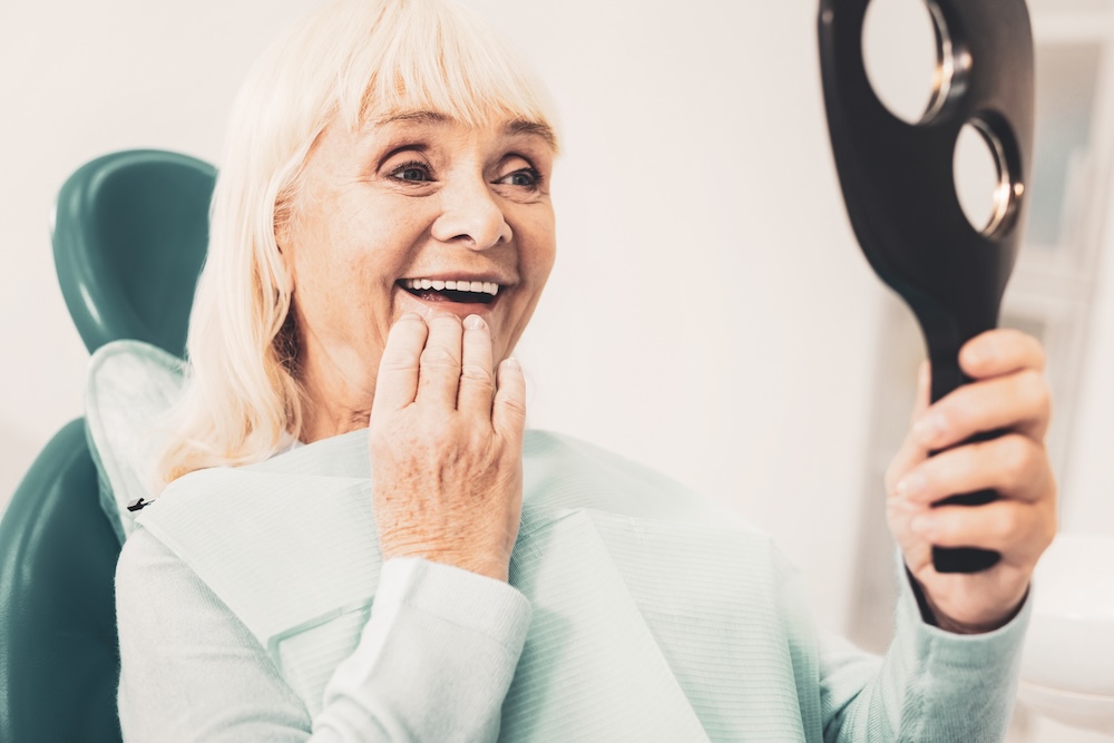 A woman holding a large black mirror in her hand.