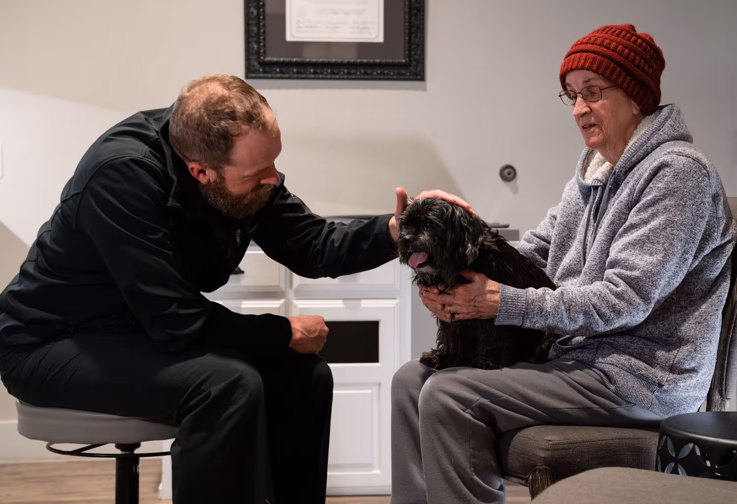 A man and a woman petting a dog.