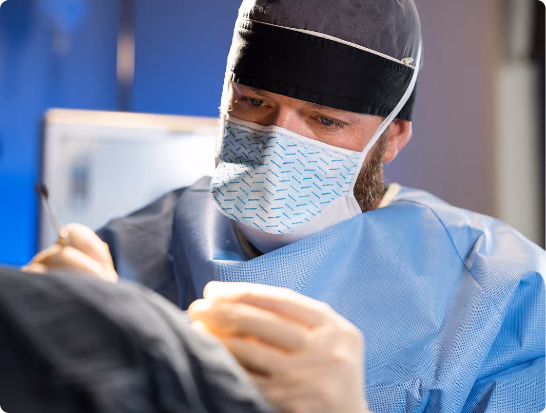 A man wearing a surgical mask and holding a tool