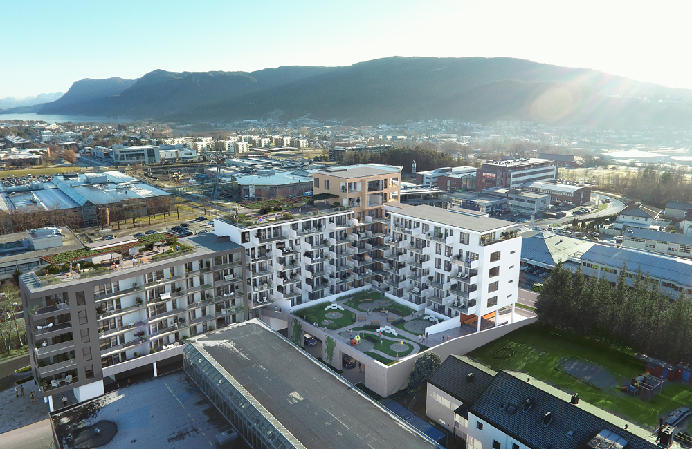 Luftperspektiv av moderne boligkompleks med takterrasser, balkonger og indre gårdsrom, omgitt av næringsbygg og natur.